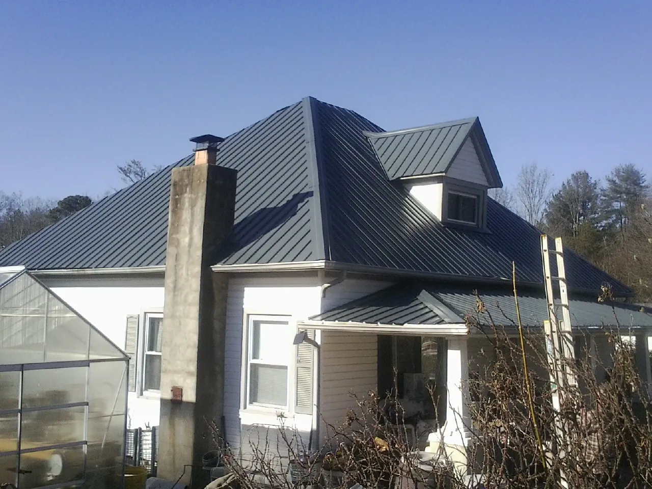 Dark blue standing seam metal roof on a white farmhouse with dormer — Slate & Tile Roof Repair by Roofing Brothers in Winnabow
