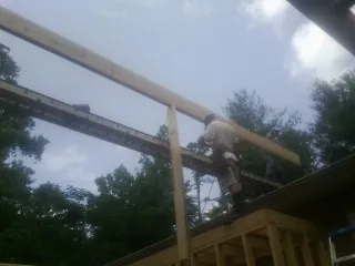 Carpenter setting a ridge beam over a new addition frame — Ice Dam Removal by Roofing Brothers in Winnabow