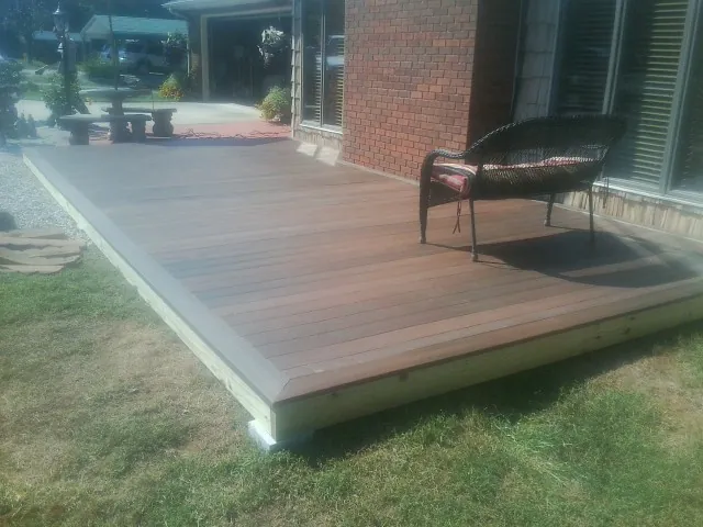 New wood deck and wicker chair beside a brick house in Winnabow