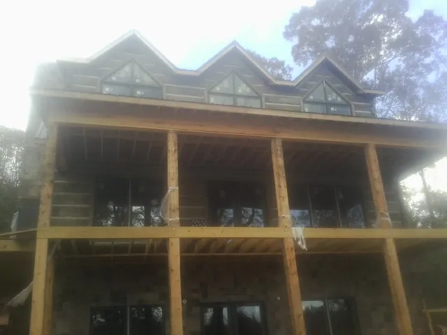 Dormers and porch framing on a large log home under construction — Roof Coating work by our crew in Winnabow