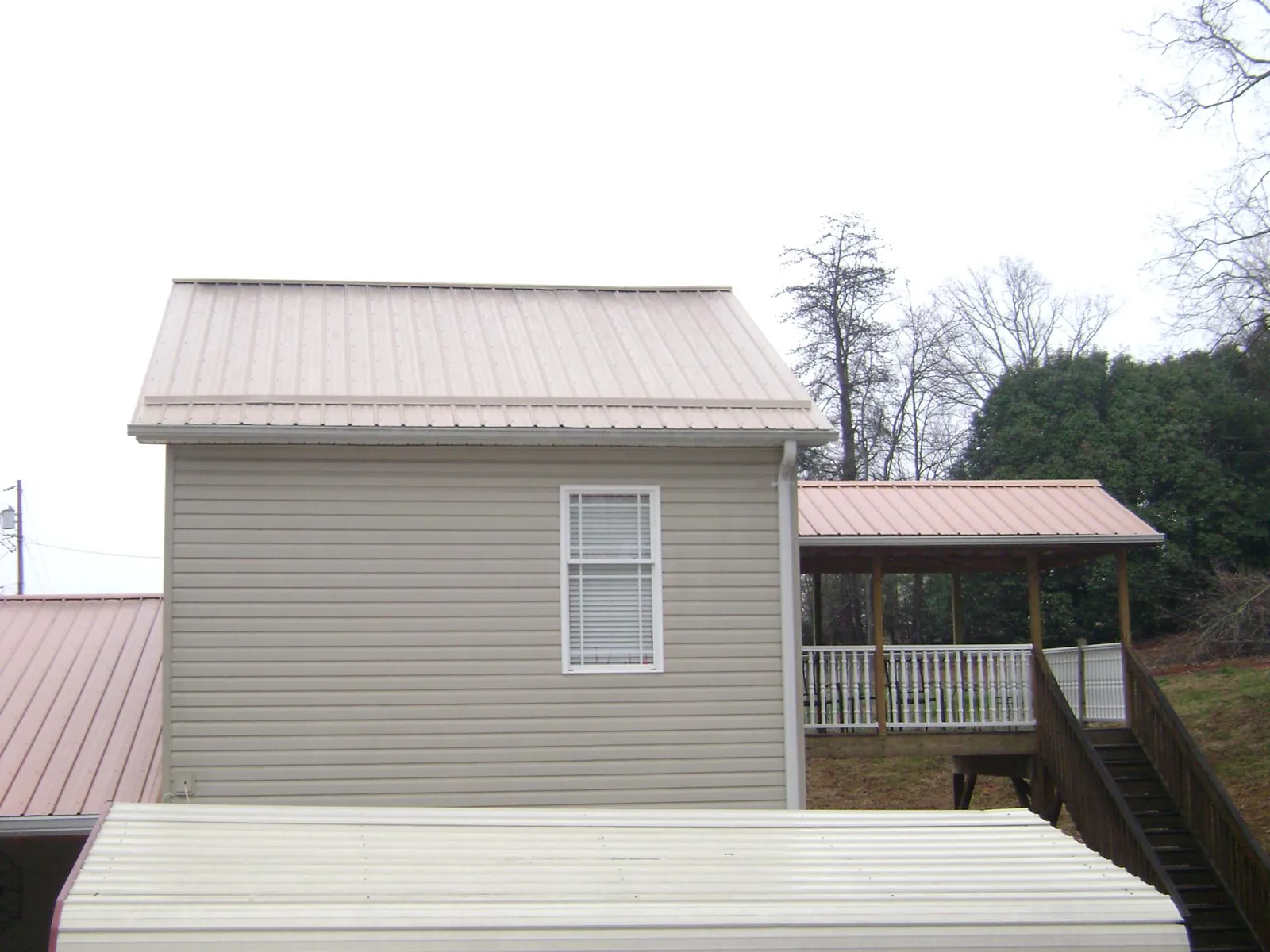 Tan metal roofs on a two story addition and attached porch, from a Roof Replacement job in Winnabow
