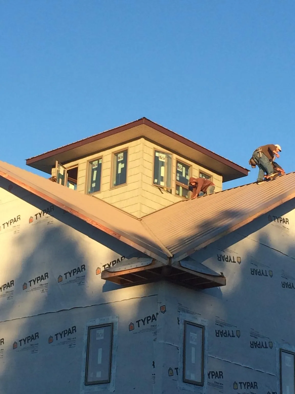 Roofers working around a rooftop cupola on a new metal roof at sunset — Roof Waterproofing in Winnabow by Roofing Brothers